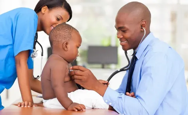 Family nurse practitioner working with nurse to take heart rate of pediatric patient